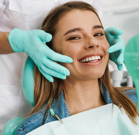 Happy patient receiving dental examination from dentist wearing gloves in modern clinic.