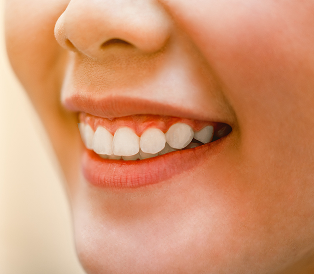 Close-up of person smiling, showing healthy white teeth and gums in dental care context.
