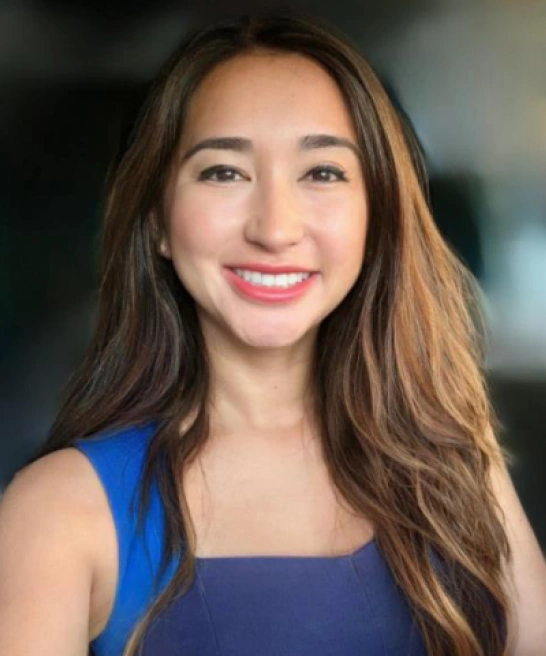 Dr. Shina, experienced family dentist in Poway, CA, standing in front of a brick wall, smiling and wearing dental loupes.