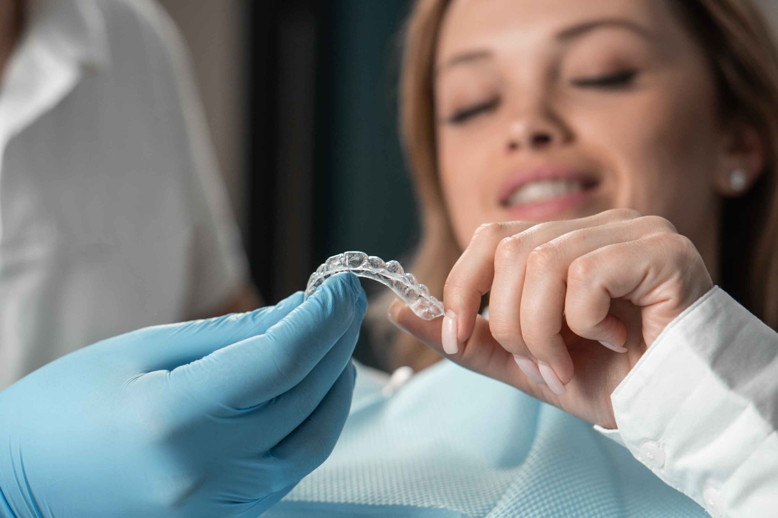 Dentist showing clear aligners to patient during Invisalign consultation.